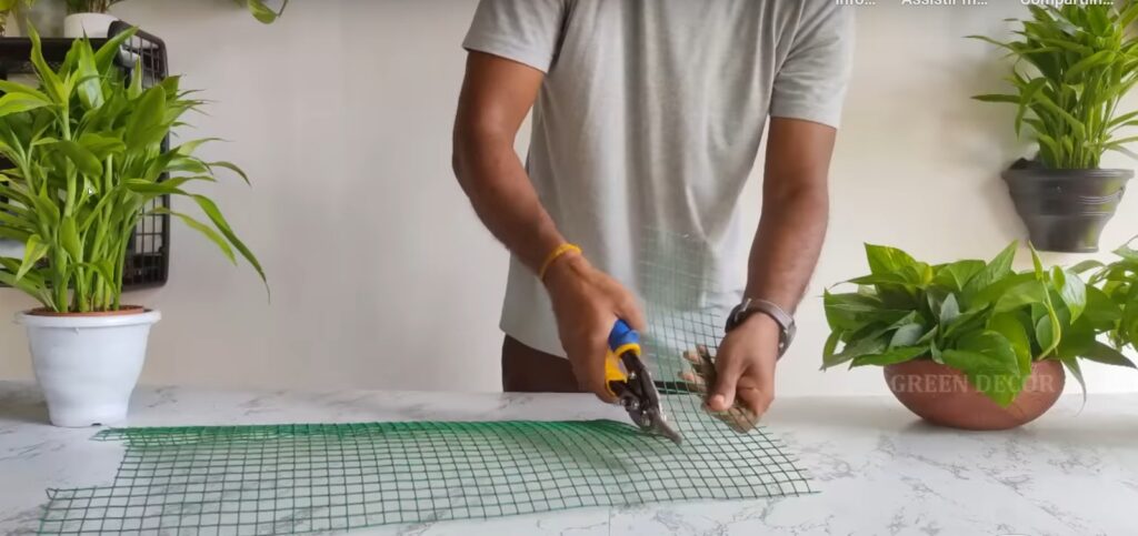 Pessoa cortando a tela metálica com a ajuda de um alicate.