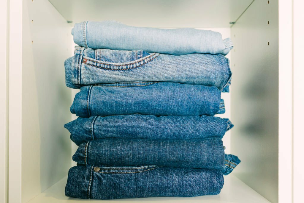 calças jeans dobradas dentro do armário em ordem de cores