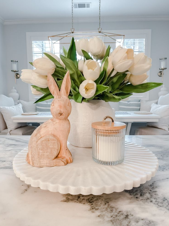 enfeite com vaso branco e tulipas brancas, coelho de páscoa de cerâmica e pote de vidro com vela. 
