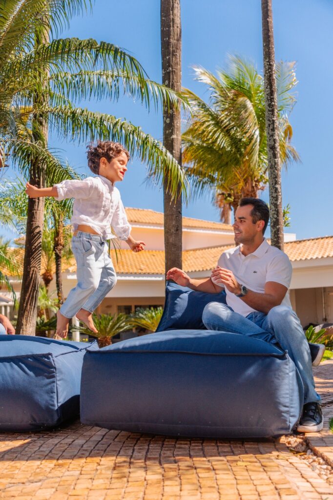 Pai e filho brincando na área externa da casa sobre móvel azul.