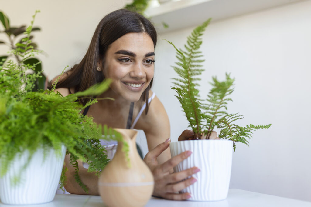 Mulher cuidando de vasos de plantas próximo a um umidificador de ar