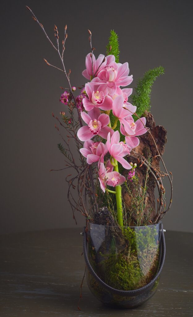 Vaso transparente com arranjo de orquídea rosa para decorar a casa na primavera.