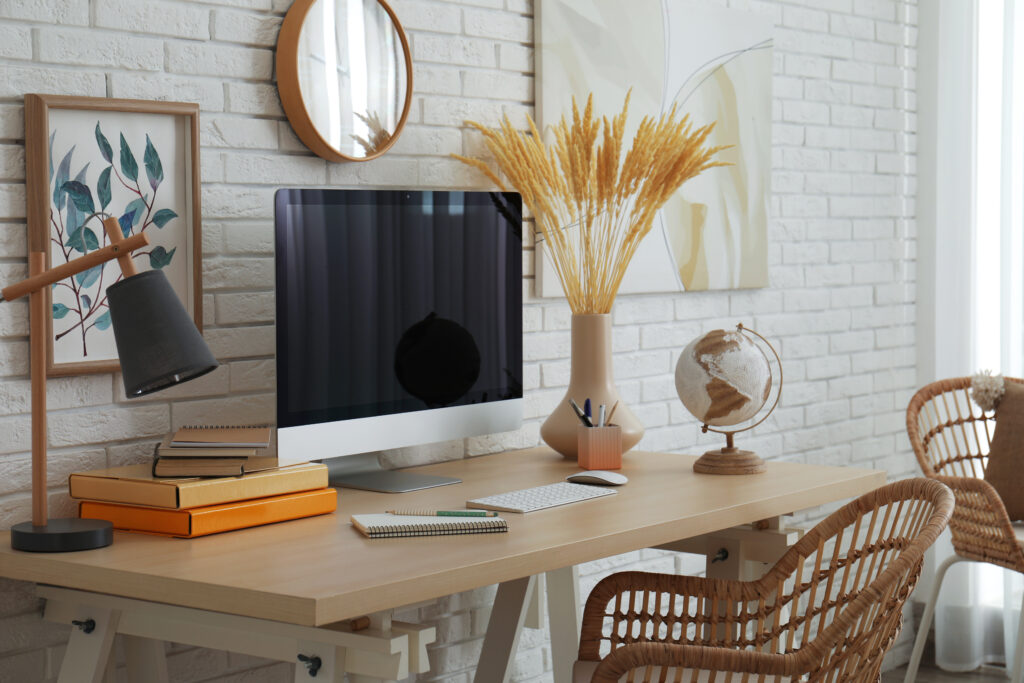 Stylish home office interior with comfortable workplace near white brick wall