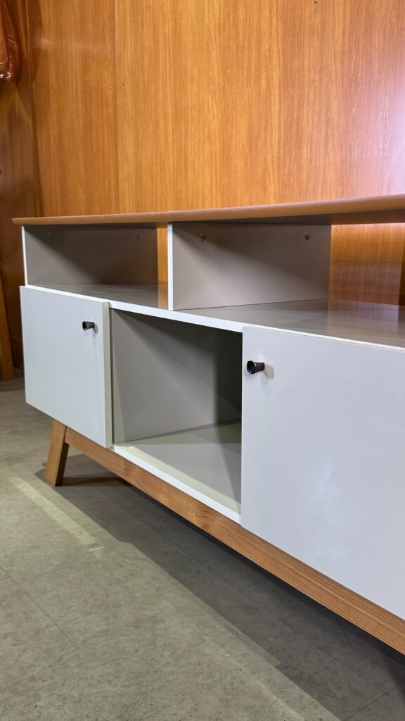 Móvel com base de madeira e pés aparentes. Acabamento com puxadores de pino redondo. 